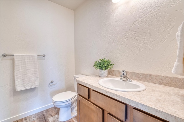 bathroom with wood-type flooring, vanity, and toilet