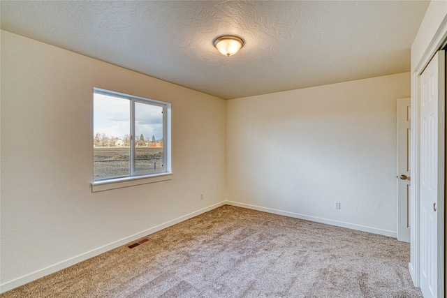 unfurnished room with light carpet and a textured ceiling