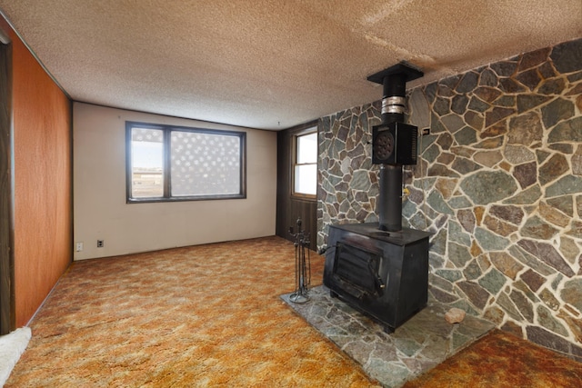 unfurnished living room with light carpet, a textured ceiling, and a wood stove