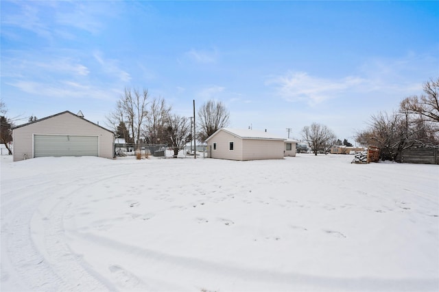 yard layered in snow featuring a garage and an outdoor structure