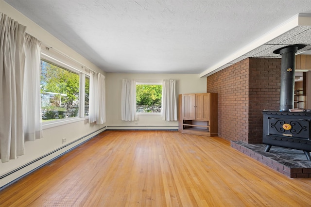 119 Fair St, Deer Lodge, MT 59722 - unfurnished living room featuring a wood stove, light wood finished floors, a baseboard heating unit, and a textured ceiling
