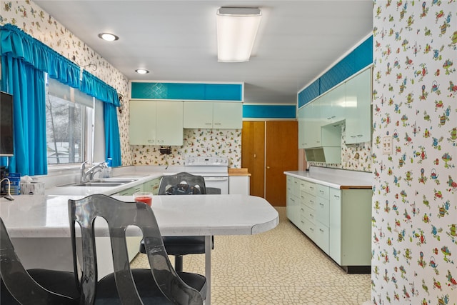 kitchen with white electric stove, kitchen peninsula, and sink