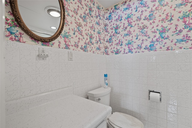 bathroom with vanity, toilet, and tile walls