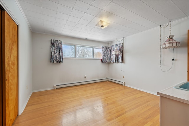 interior space with a baseboard radiator, ornamental molding, sink, and hardwood / wood-style floors