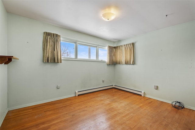 unfurnished room featuring a baseboard heating unit and wood-type flooring