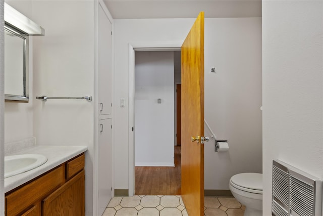 bathroom featuring heating unit, vanity, tile patterned floors, and toilet