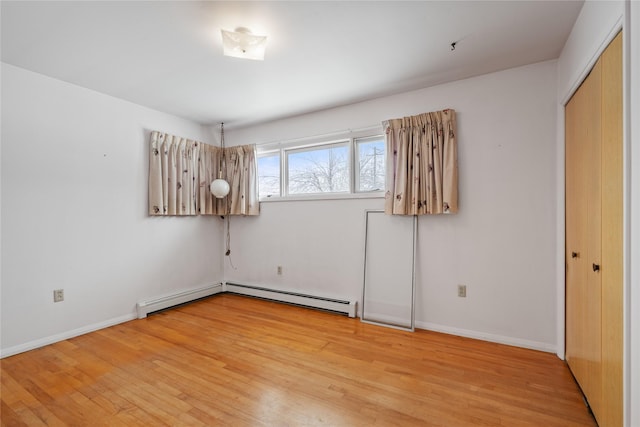 empty room with a baseboard radiator and light hardwood / wood-style floors