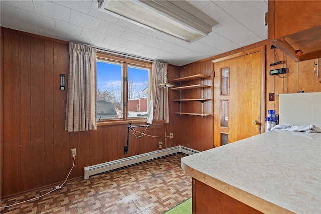 interior space with dark parquet floors, baseboard heating, and wood walls