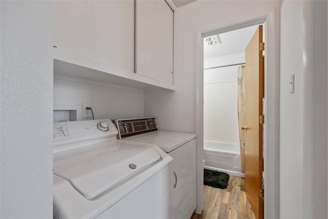 laundry area with cabinets, washing machine and clothes dryer, and light hardwood / wood-style flooring