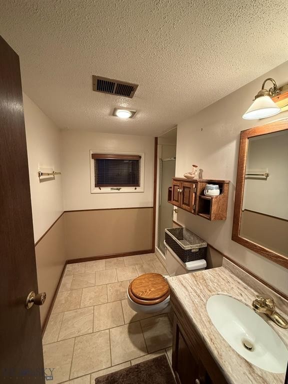 3435 Parkway St, Butte, MT 59701 - full bathroom featuring a textured ceiling, vanity, a shower with shower door, toilet, and visible vents