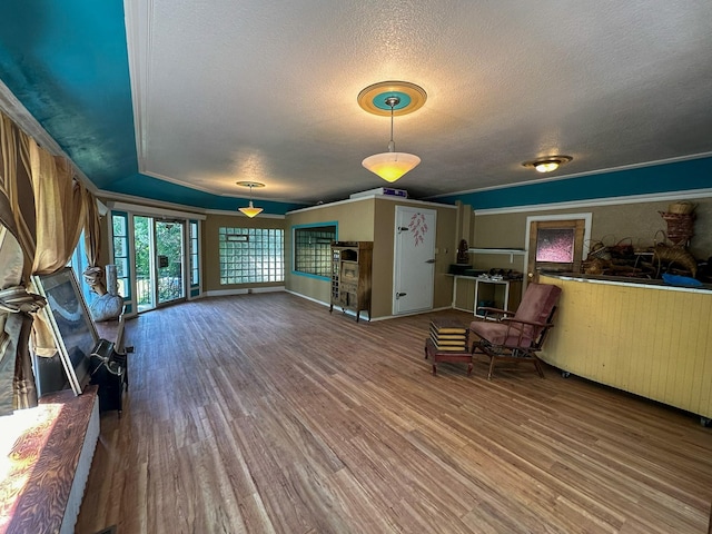 sitting room with hardwood / wood-style flooring, crown molding, and a textured ceiling