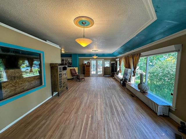 corridor featuring wood-type flooring, ornamental molding, french doors, and a textured ceiling