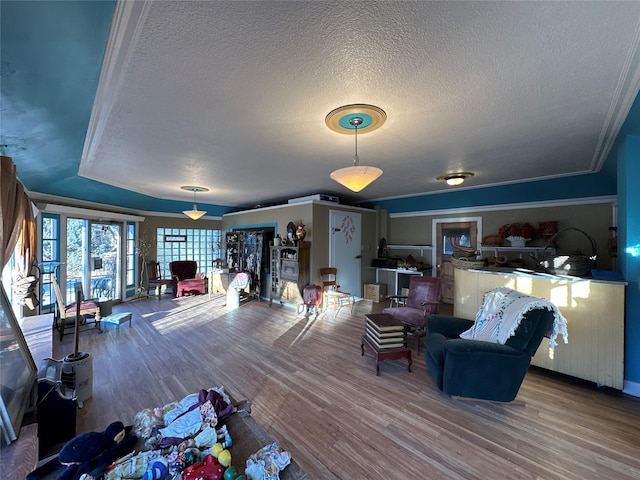 living room with crown molding, wood-type flooring, and a textured ceiling