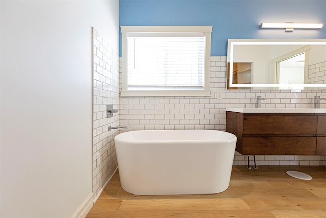 bathroom featuring a washtub, hardwood / wood-style floors, vanity, and tile walls