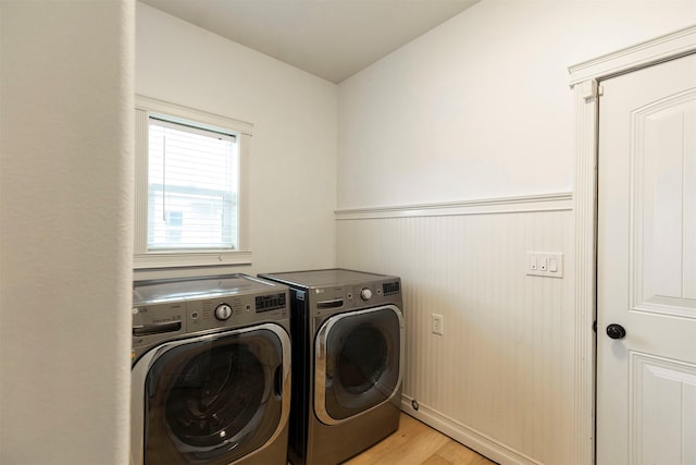 washroom with washing machine and clothes dryer and light hardwood / wood-style flooring