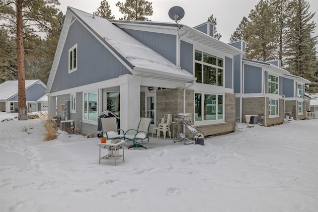 snow covered house featuring central AC unit