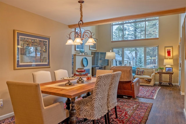 dining room featuring baseboards, a towering ceiling, wood finished floors, and a chandelier