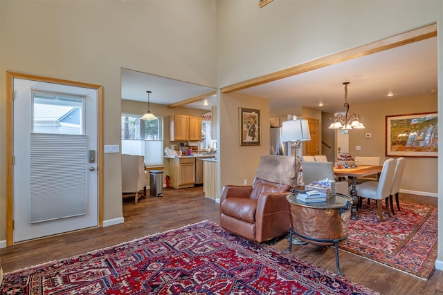 living area with dark wood-type flooring, baseboards, and a notable chandelier