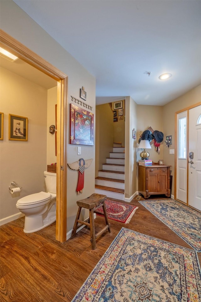 foyer featuring baseboards, stairs, and wood finished floors