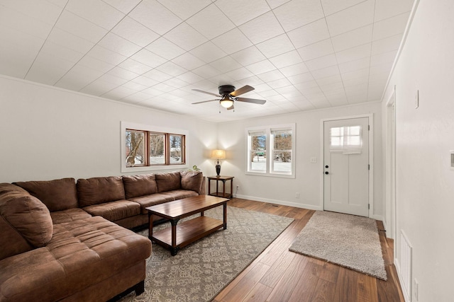 living room featuring wood-type flooring, ceiling fan, and crown molding