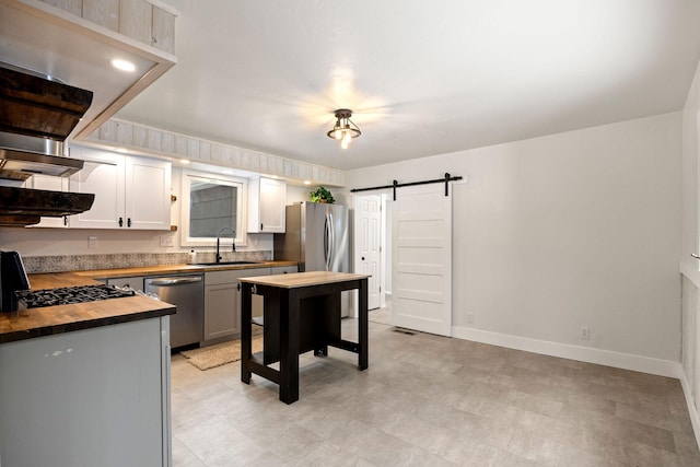 kitchen with sink, wooden counters, gray cabinets, stainless steel appliances, and a barn door