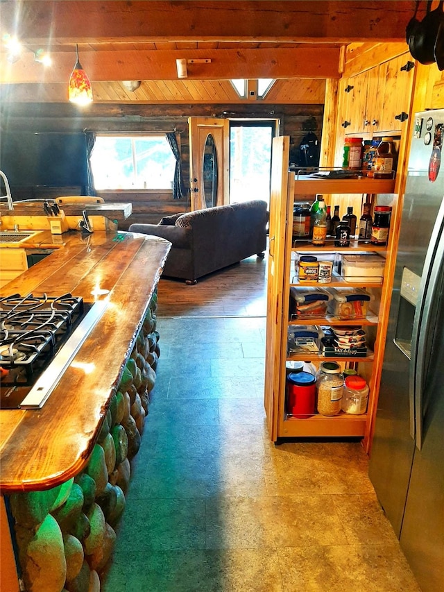 kitchen with stainless steel refrigerator with ice dispenser, sink, stovetop, and pendant lighting