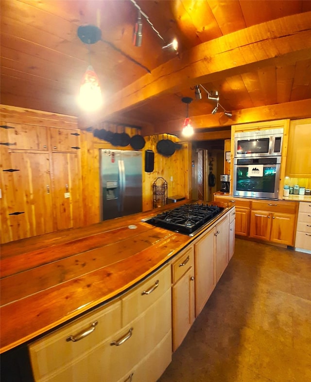 kitchen with appliances with stainless steel finishes, pendant lighting, wood walls, wooden ceiling, and beam ceiling