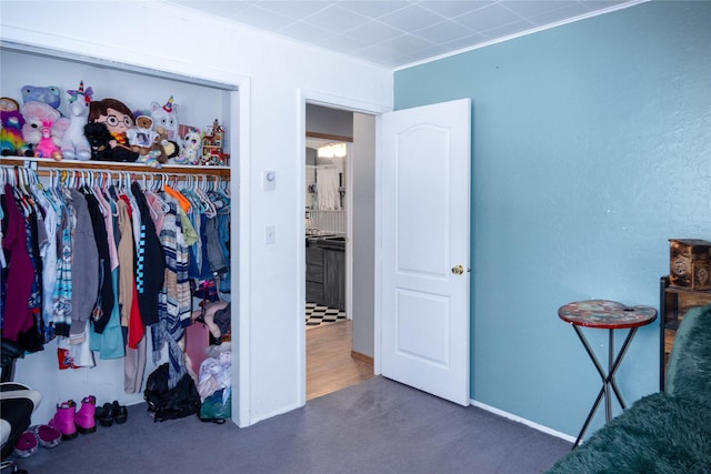 bedroom featuring dark colored carpet, crown molding, and a closet