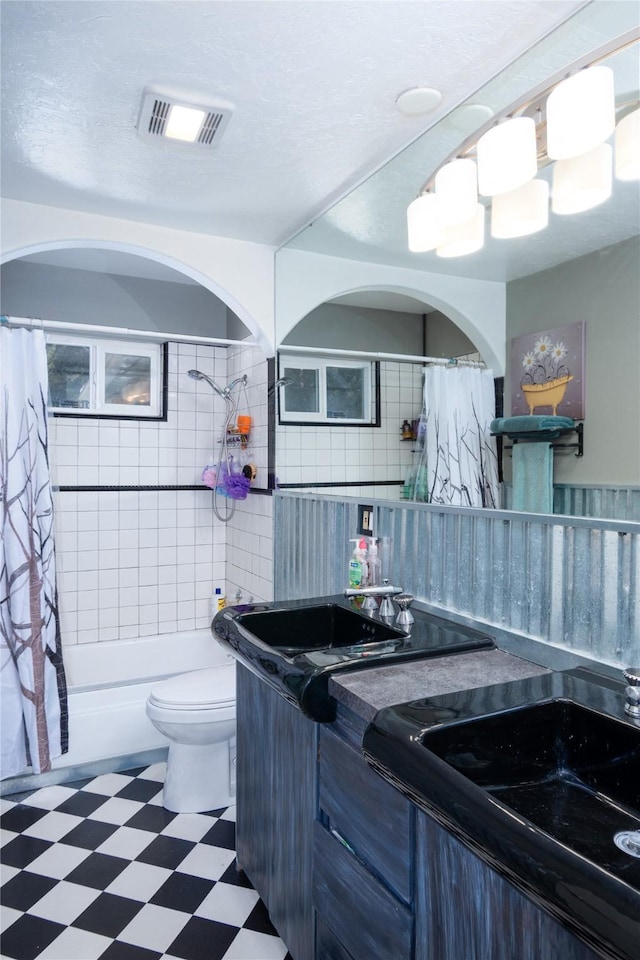 full bathroom featuring shower / tub combo, backsplash, tile walls, vanity, and toilet