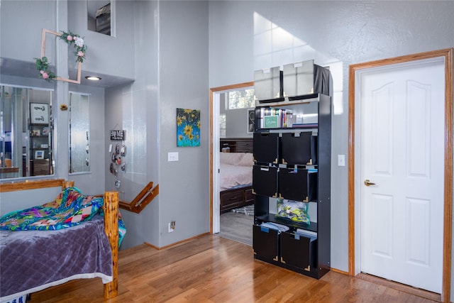 bedroom with a towering ceiling and light wood-type flooring