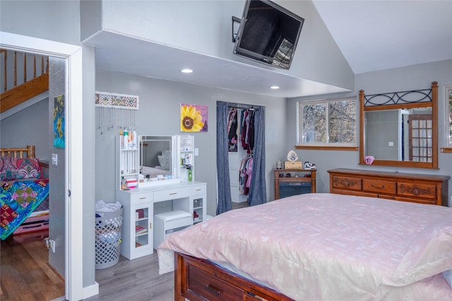 bedroom with wood-type flooring, lofted ceiling, and a closet