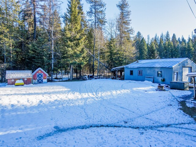 yard layered in snow featuring an outdoor fire pit and a shed