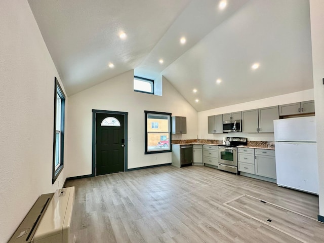 kitchen featuring appliances with stainless steel finishes, high vaulted ceiling, sink, gray cabinetry, and light wood-type flooring