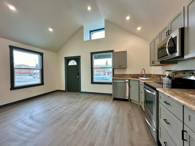 kitchen with high vaulted ceiling, sink, gray cabinetry, light hardwood / wood-style floors, and stainless steel appliances