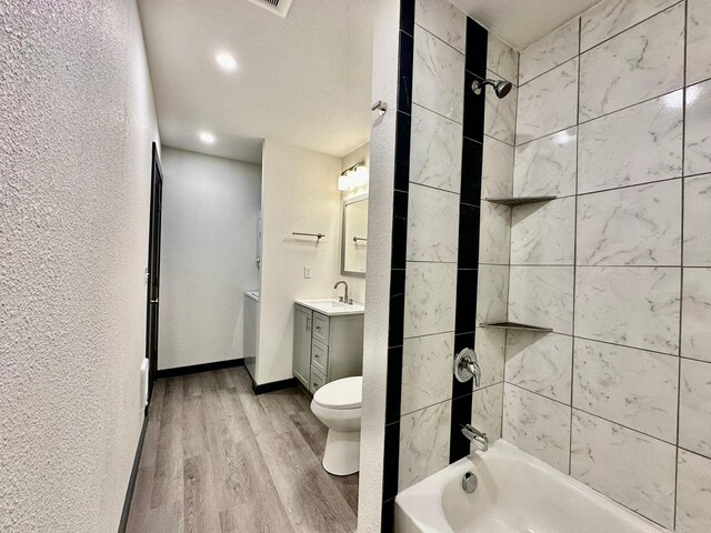 full bathroom featuring vanity, toilet, tiled shower / bath combo, and hardwood / wood-style floors