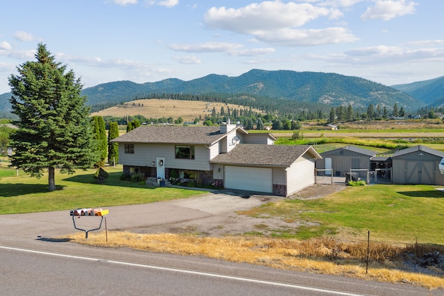 exterior space with a mountain view, a garage, and a front lawn