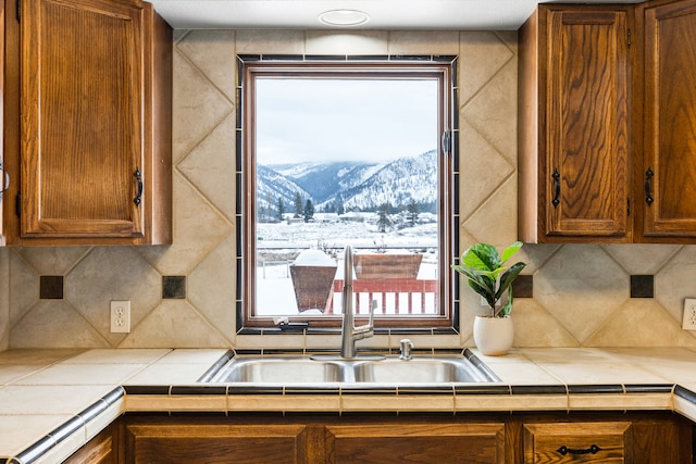 kitchen with a mountain view, sink, tile counters, and backsplash