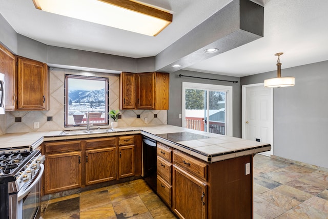 kitchen featuring decorative light fixtures, black appliances, tile counters, kitchen peninsula, and backsplash