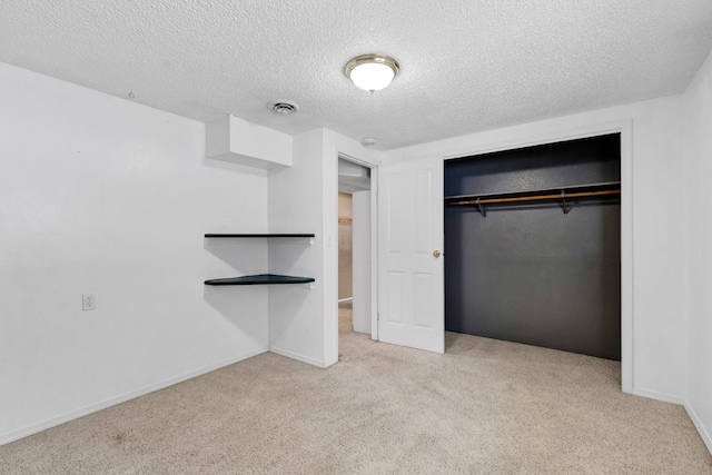 unfurnished bedroom with light colored carpet, a closet, and a textured ceiling