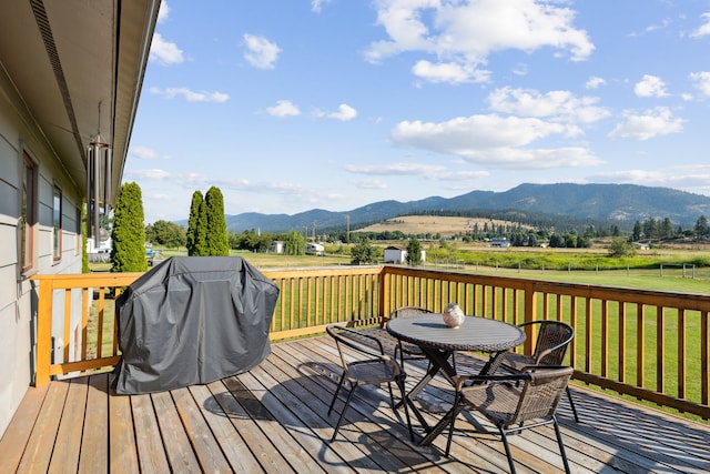 deck with area for grilling, a mountain view, and a yard