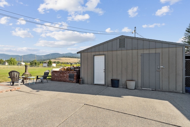 view of outbuilding featuring a mountain view, a fire pit, and a lawn