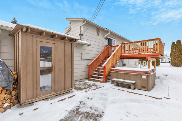 snow covered house with a hot tub and a wooden deck