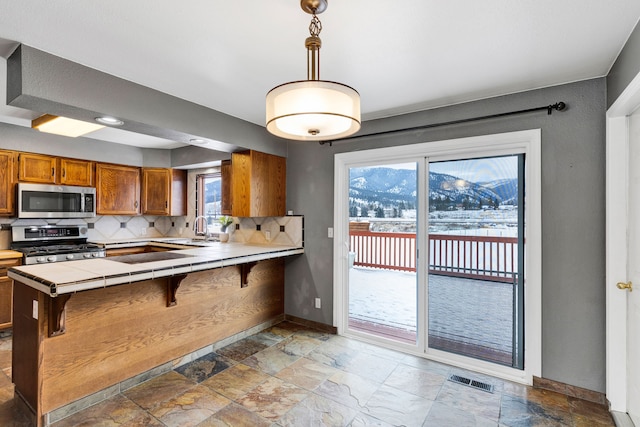 kitchen featuring appliances with stainless steel finishes, pendant lighting, tasteful backsplash, sink, and a breakfast bar area