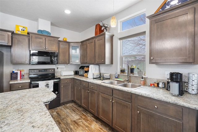 kitchen with light stone countertops, sink, pendant lighting, and stainless steel electric range