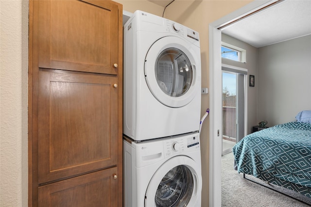 laundry area with cabinets, stacked washer and dryer, and carpet