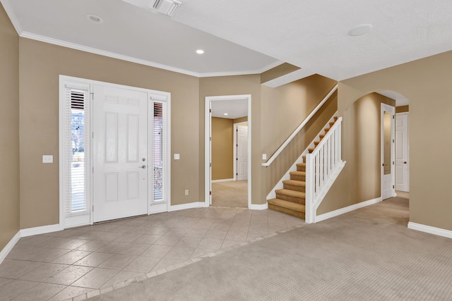 entryway with crown molding and light tile patterned flooring