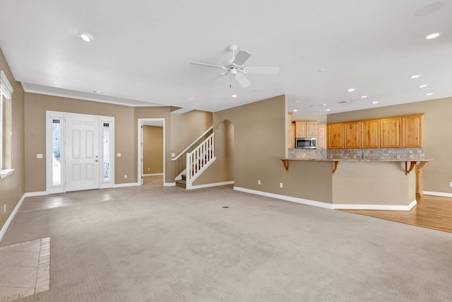 unfurnished living room with light colored carpet and ceiling fan