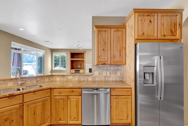 kitchen with sink, a textured ceiling, ceiling fan, stainless steel appliances, and decorative backsplash