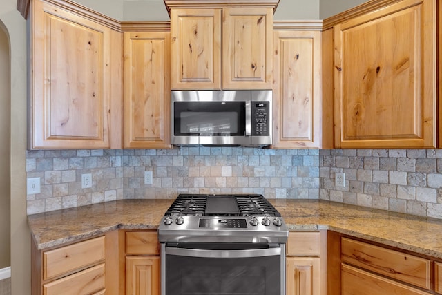 kitchen featuring stainless steel appliances, light brown cabinets, and decorative backsplash