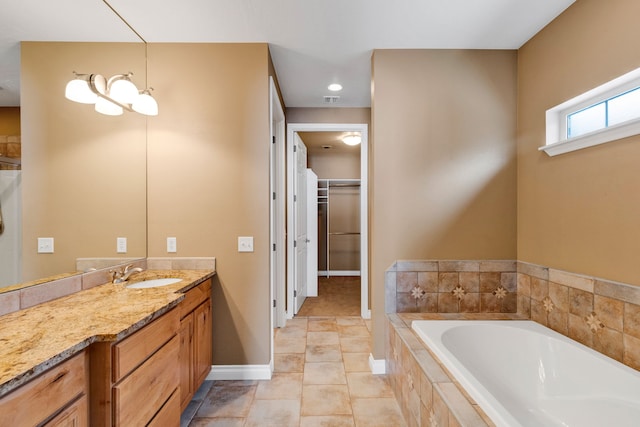 bathroom featuring tile patterned flooring, vanity, and a relaxing tiled tub